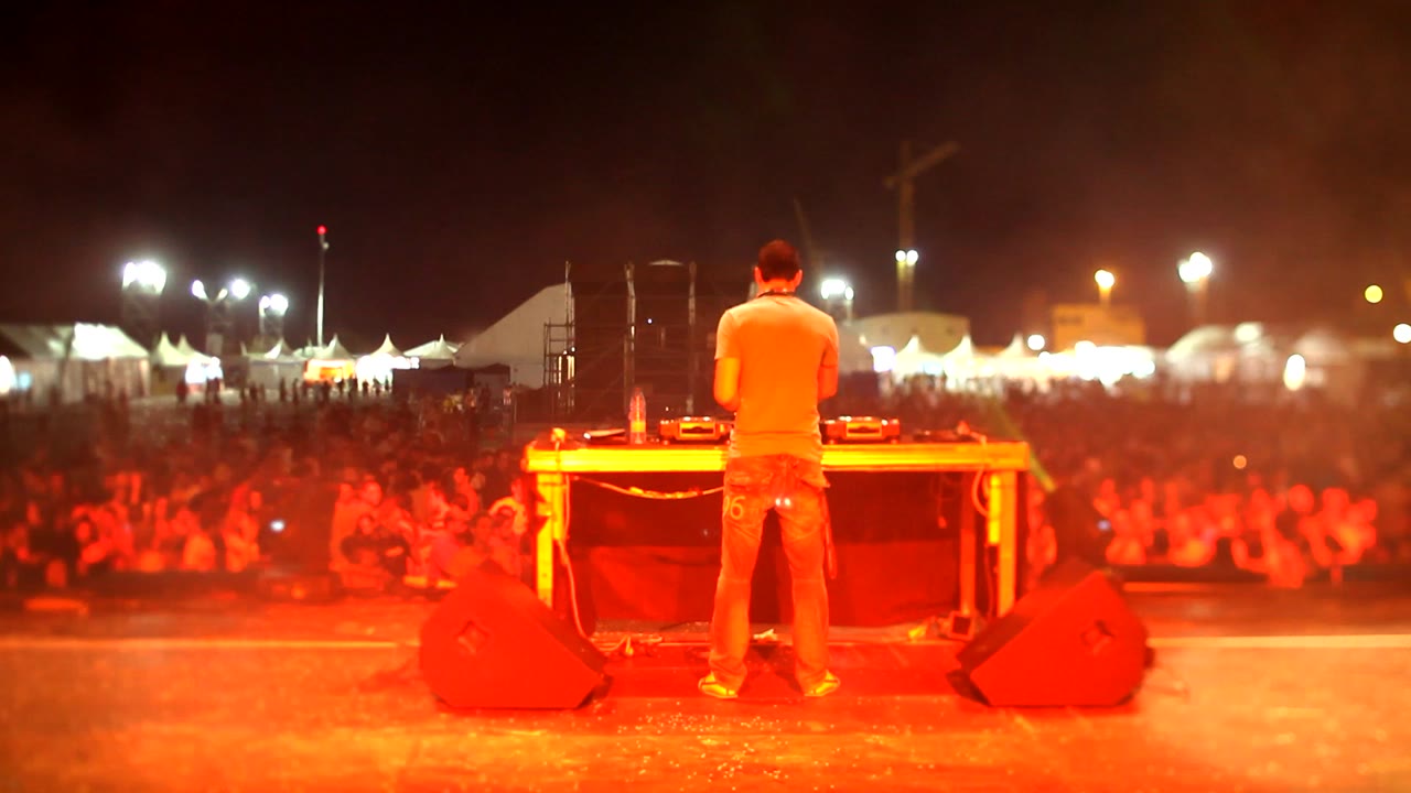A DJ playing to a crowd under stage lights — stock mood photograph